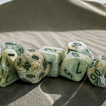 Green marble 7-die set for tabletop gaming, featuring dark green and lighter green hues, from THE MIGHTY HOBBY SHOP.