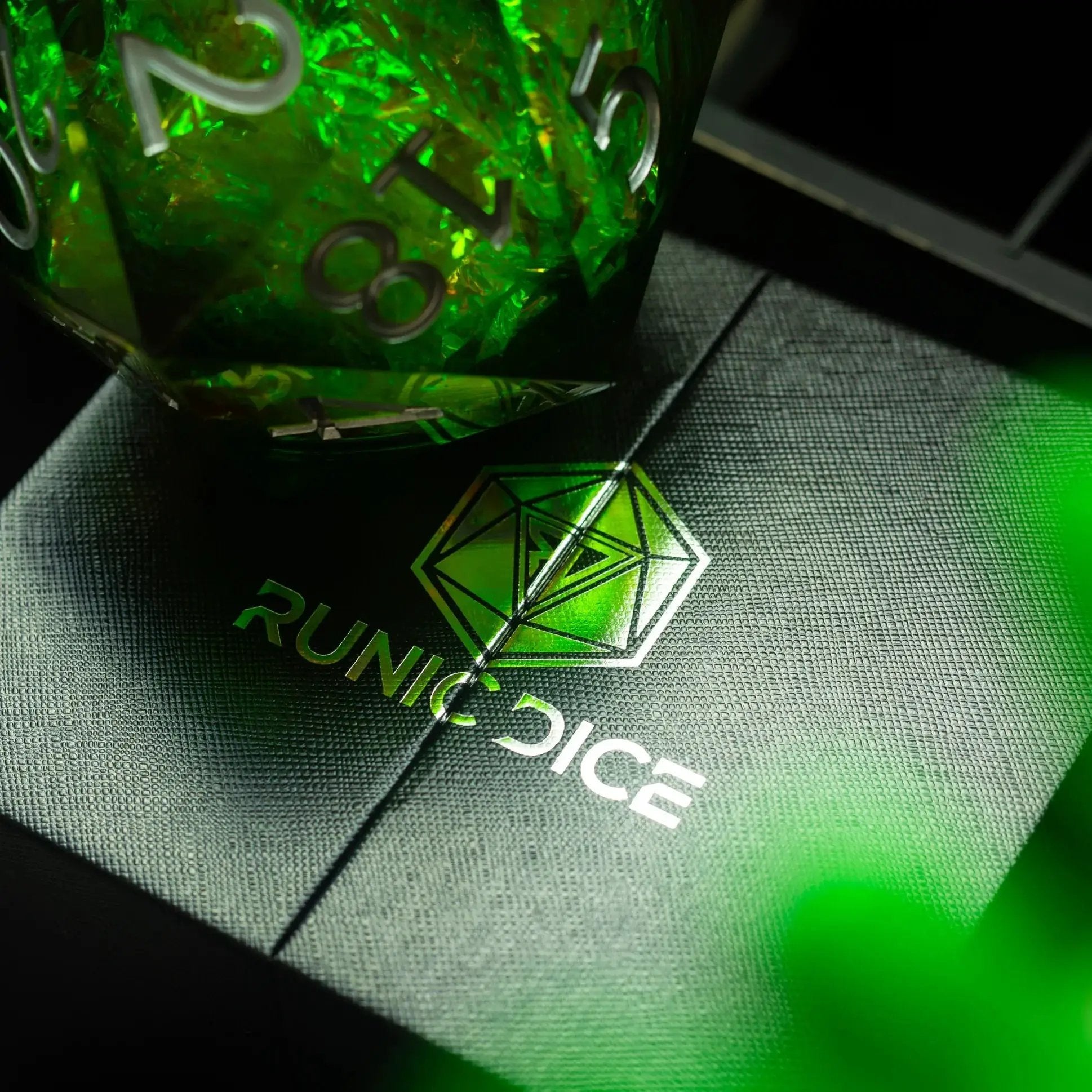 Large green resin D20 dice with liquid core, handmade by Runic Dice, displayed alongside its matching storage box.