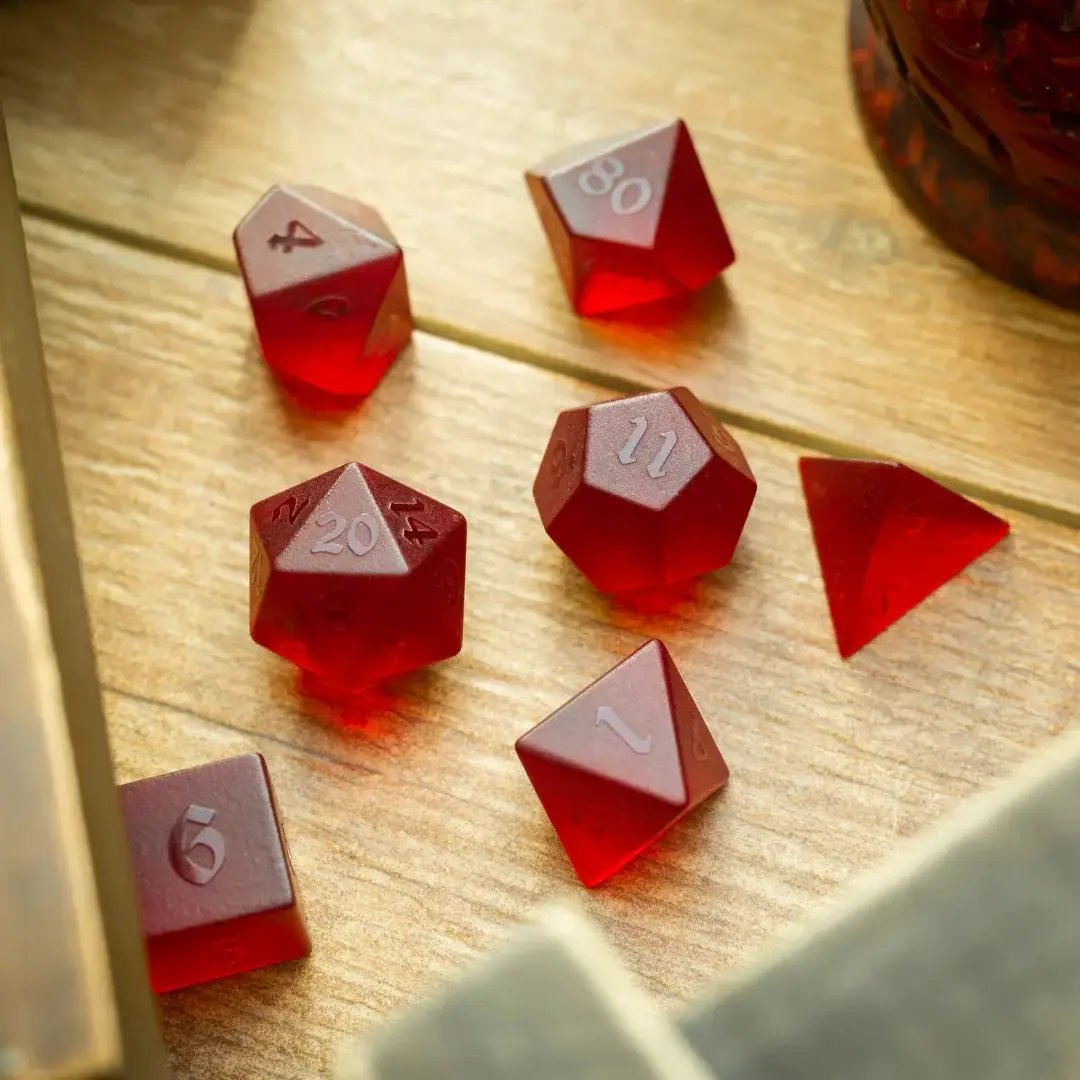 Blood red raised zircon glass gemstone DND dice set, hand-carved by Runic Dice, featuring detailed geometric patterns and a vibrant red hue.