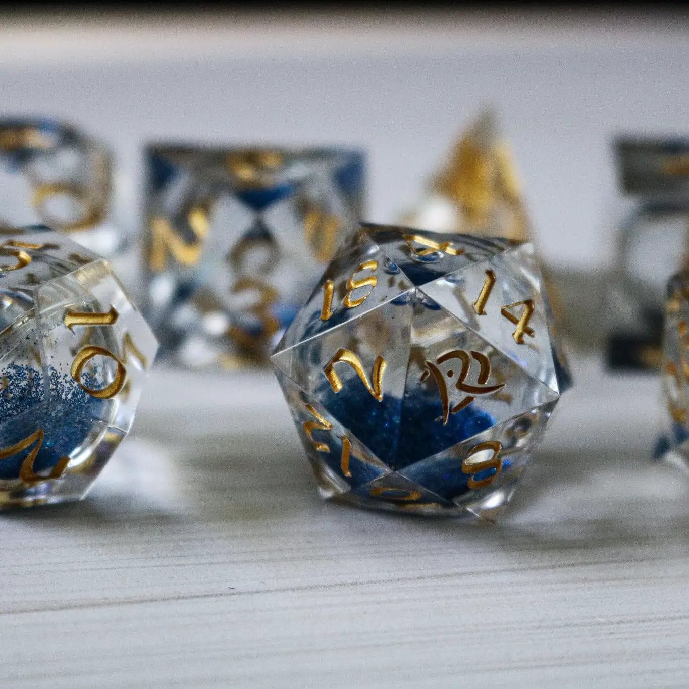 Blue glitter liquid core resin DND dice set by Runic Dice, handmade sharp edge design for tabletop gaming.