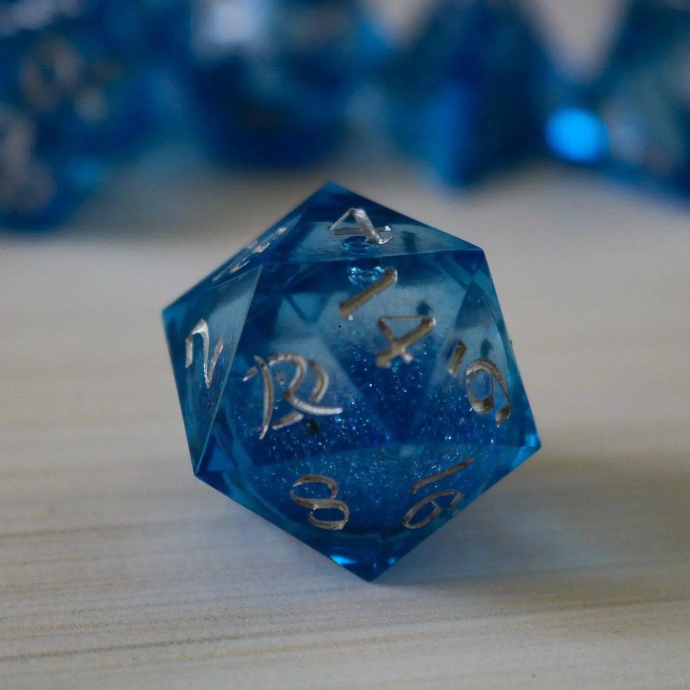 Blue glitter liquid core sharp edge handmade resin DND dice set by Runic Dice, featuring six vibrant, sparkling polyhedral dice.