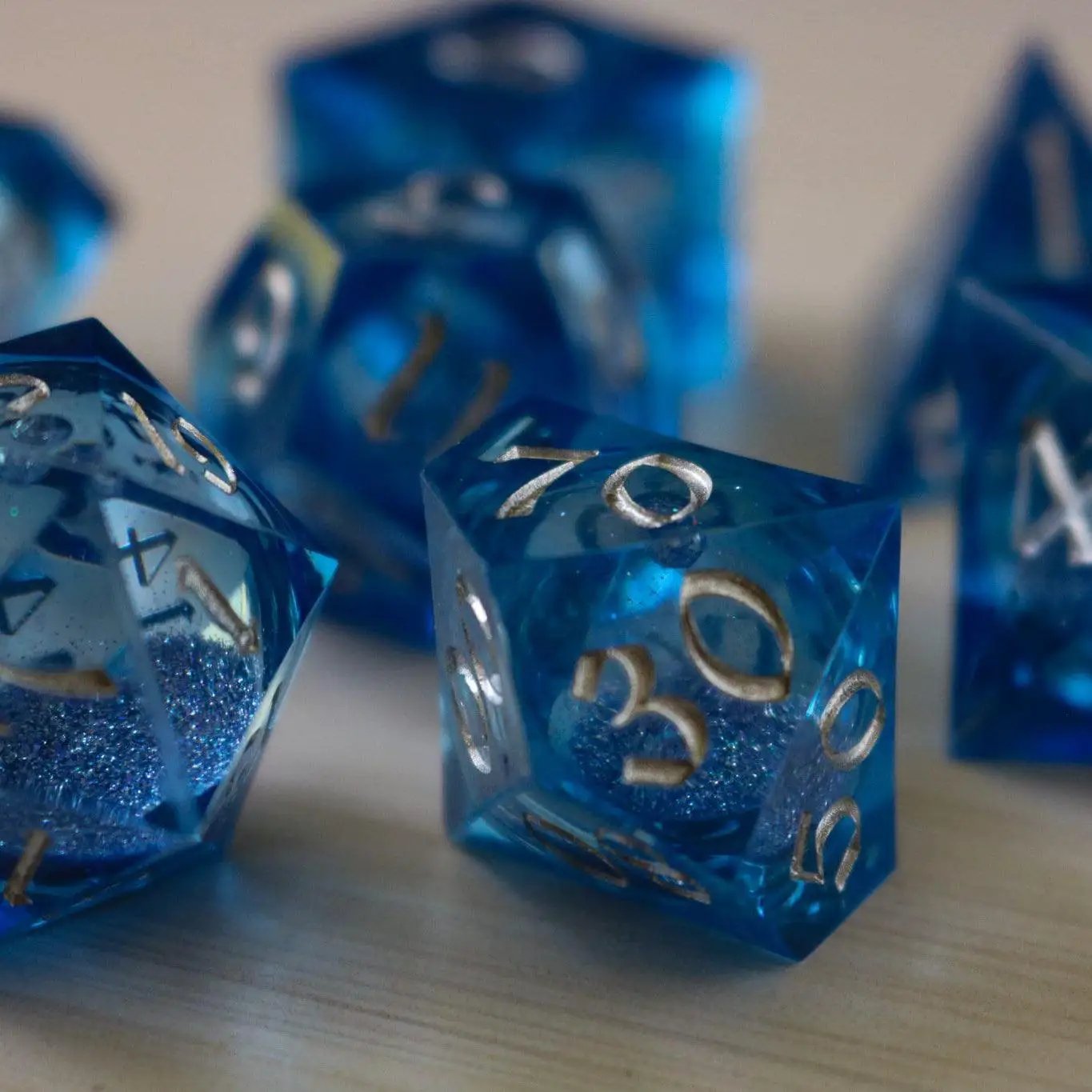 Blue glitter liquid core sharp edge handmade resin DND dice set by Runic Dice, featuring vibrant blue colors and intricate design.