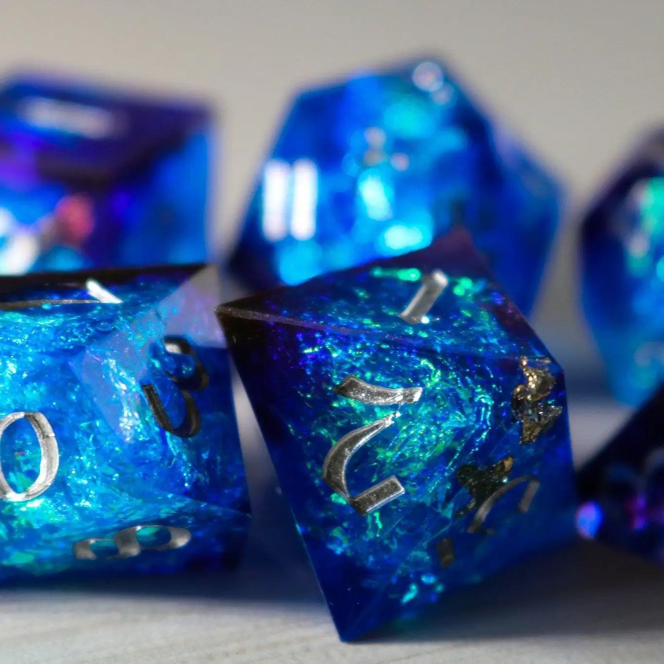 Blue handmade resin DND dice set with sharp edges, featuring six pieces in various shades of blue, crafted by Runic Dice.