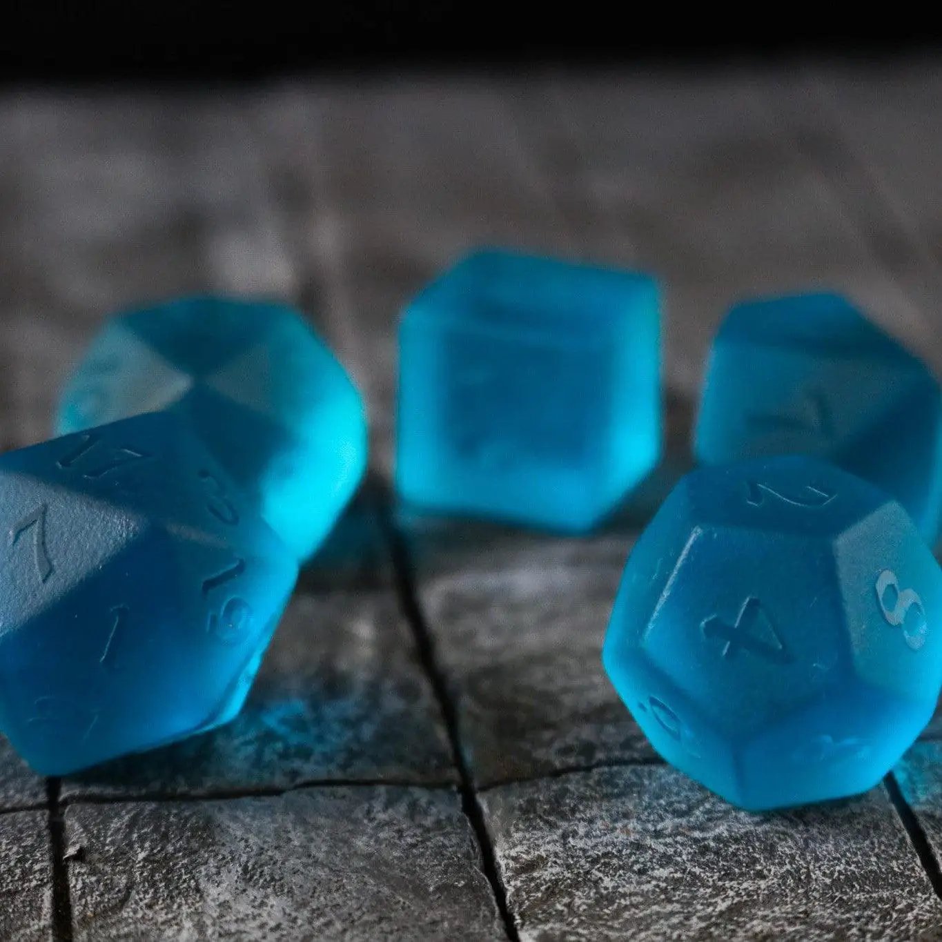 Blue zircon gemstone dice set with hand-carved glass D&D dice featuring intricate details and vibrant blue color.