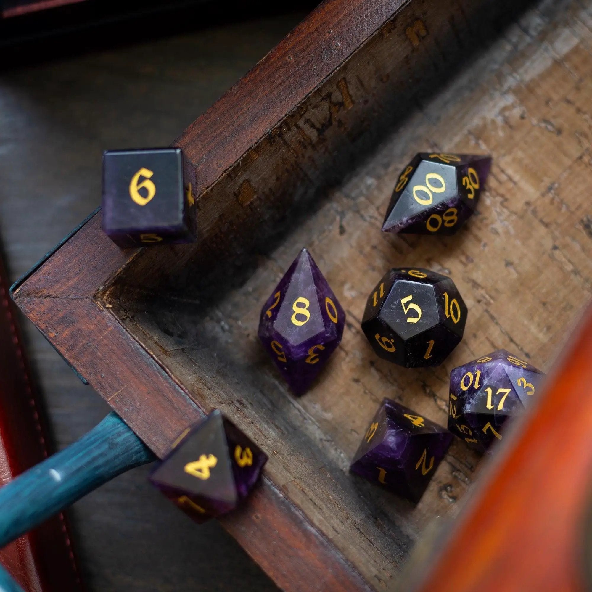 Purple amethyst gemstone DND dice set with elven cut design by Runic Dice, featuring seven intricately carved gemstone dice.