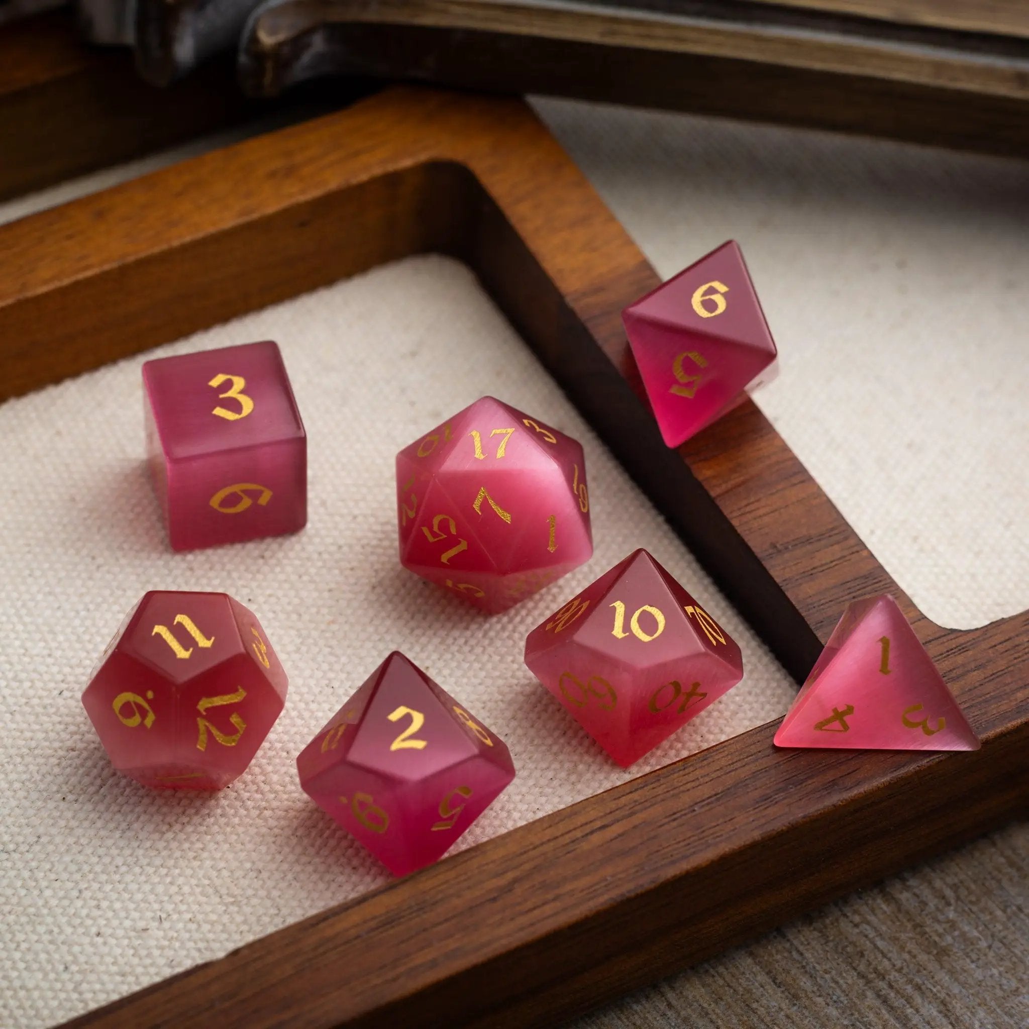 Hand-carved gemstone Rose Red Cats Eye DND dice set by Runic Dice featuring vibrant, polished gemstone dice for tabletop gaming.