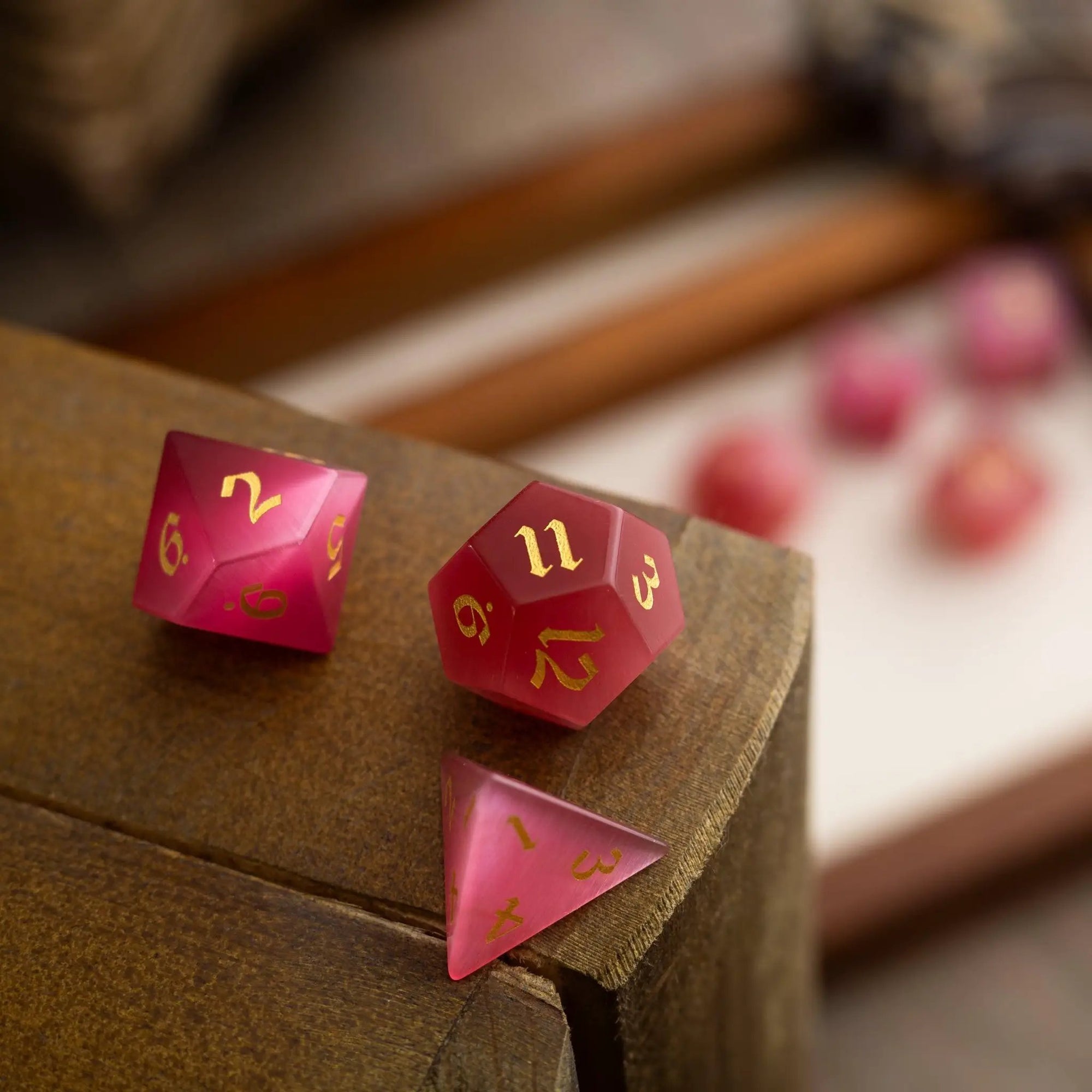 Hand-carved gemstone Rose Red Cats Eye DND dice set by Runic Dice, featuring polished, vibrant red stone with detailed carvings.