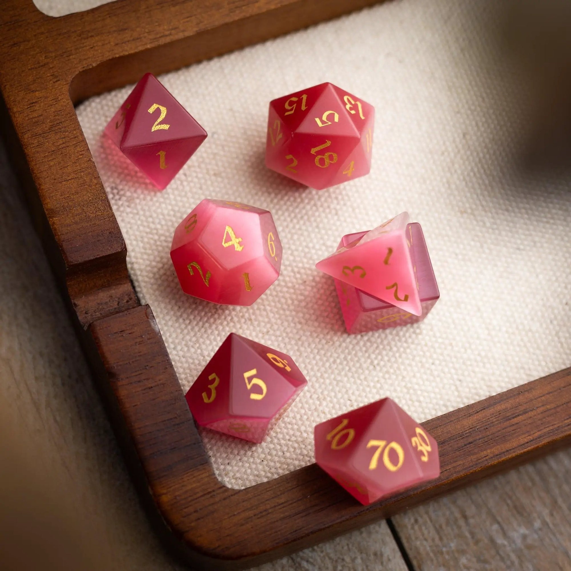 Hand-carved gemstone Rose Red Cats Eye DND dice set by Runic Dice, featuring vibrant, polished gemstone dice for tabletop gaming.