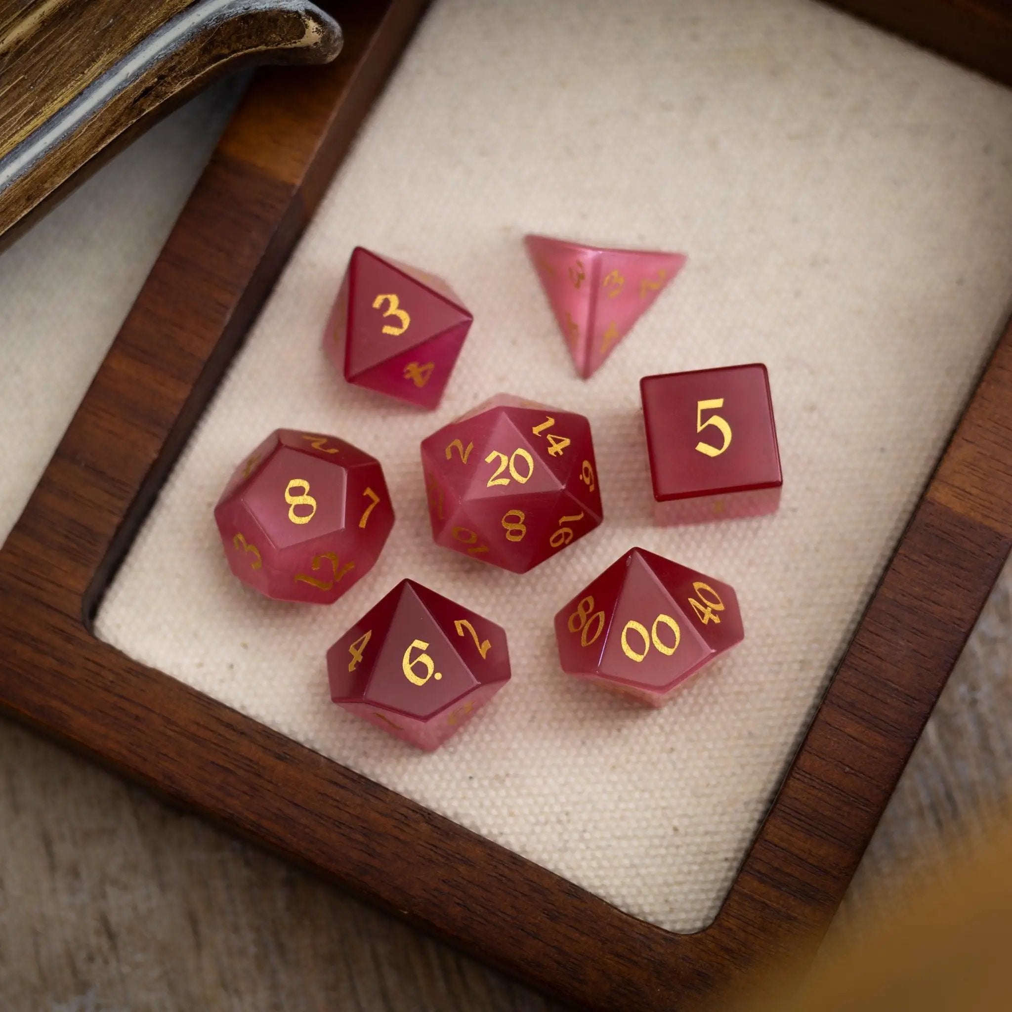 Hand-carved gemstone dice set featuring rose red cats eye stones for DND gaming by Runic Dice.