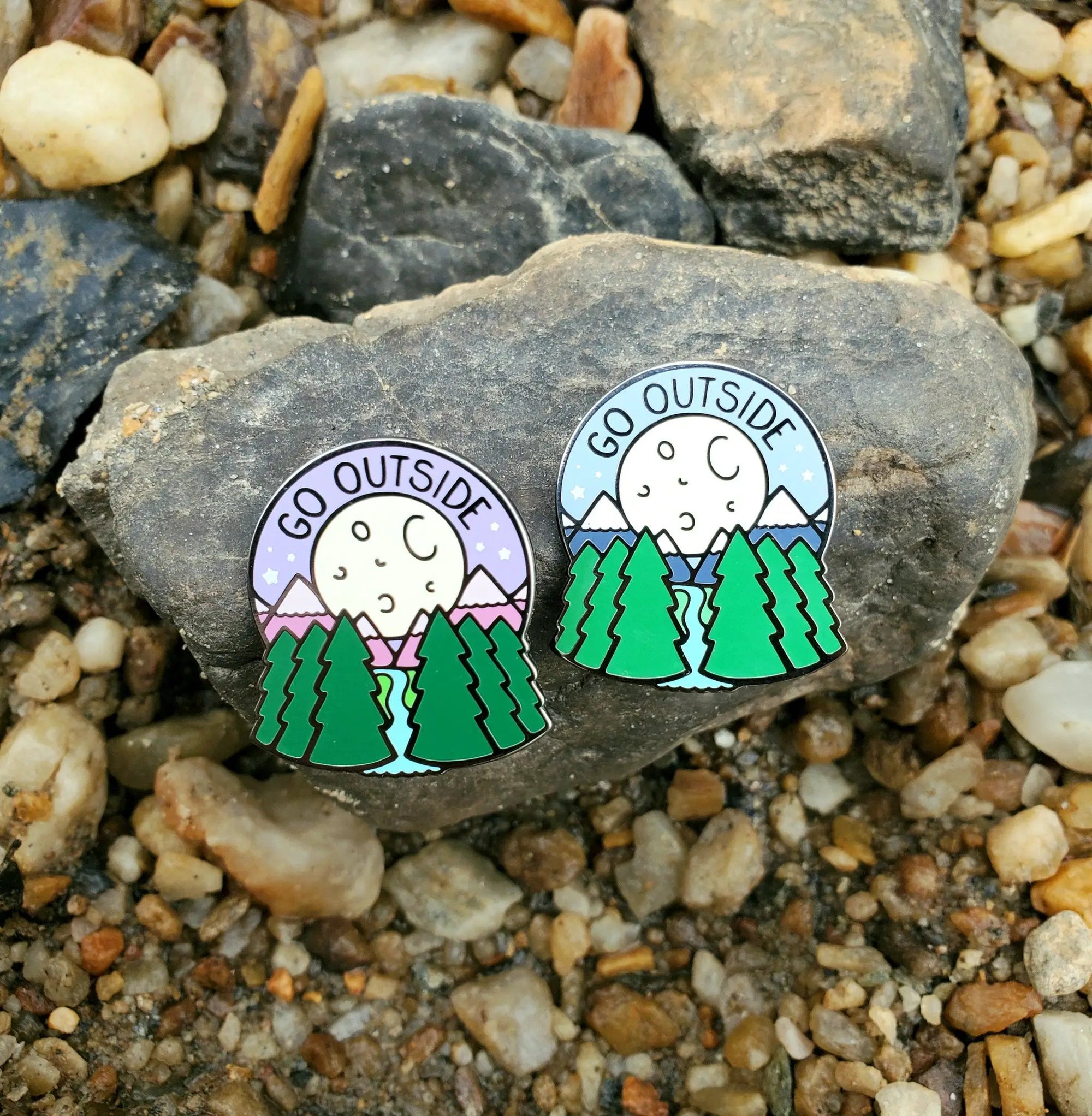 Kolorspun Go Outside pin displayed on a rock, featuring outdoor-themed design perfect for hats or backpacks.