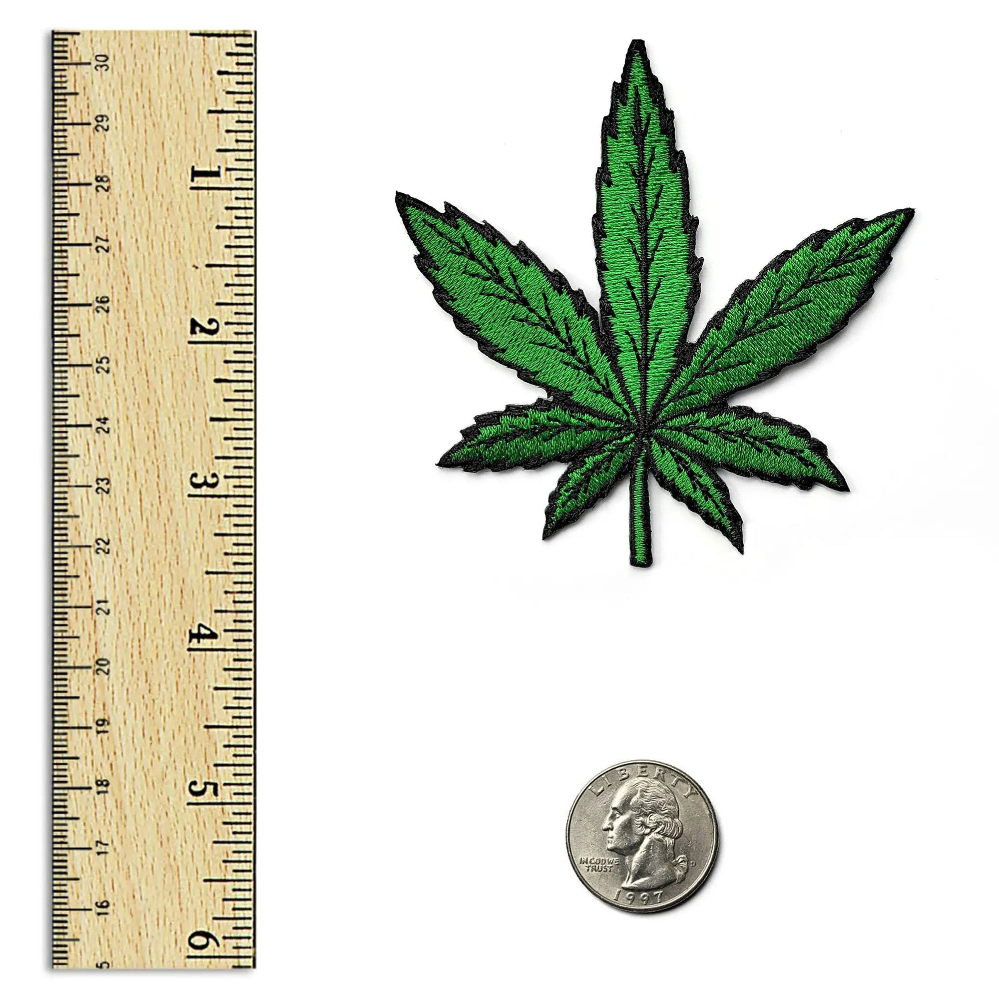 Kolorspun cannabis leaf patch shown on a vertical ruler, displaying detailed green leaf design on fabric patch.