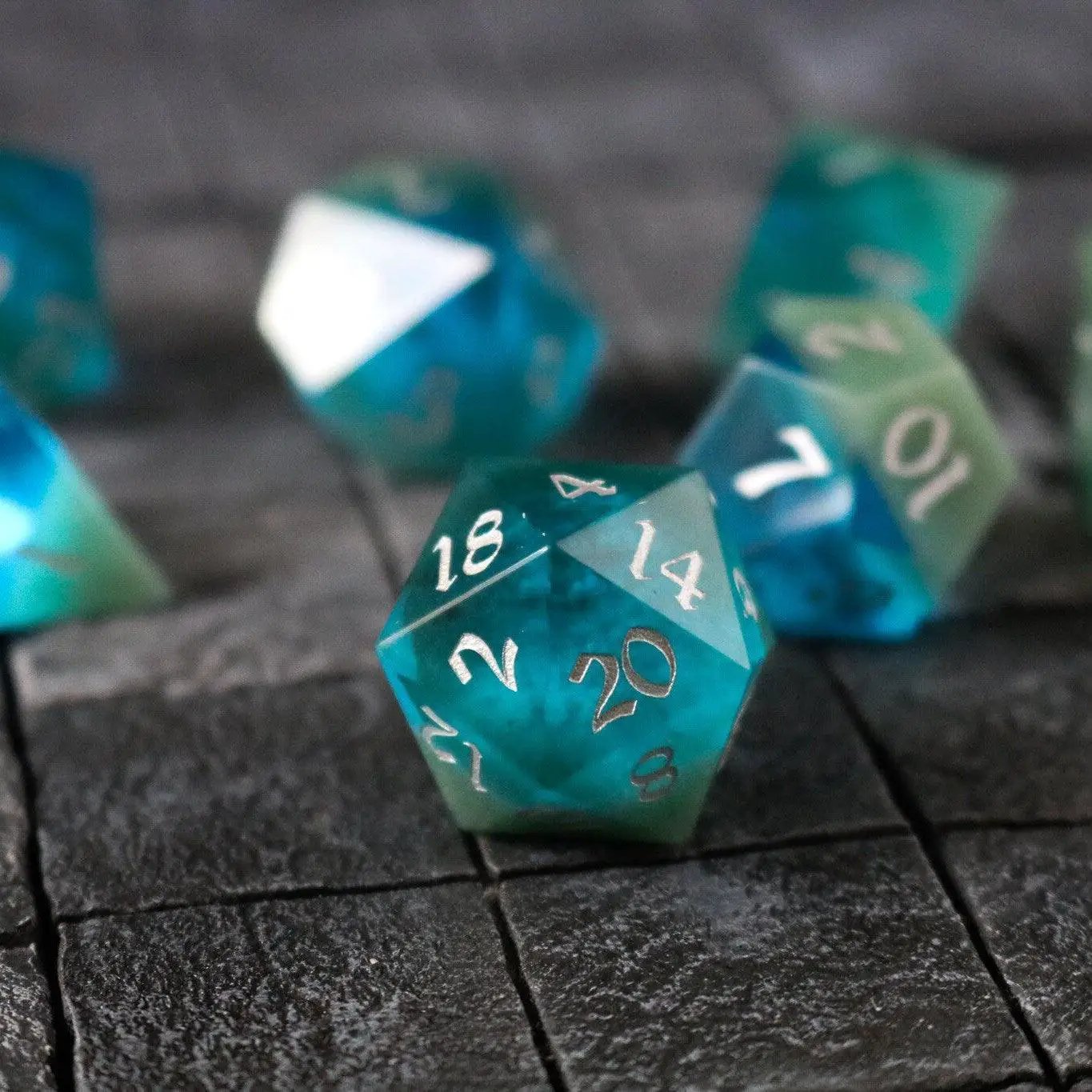 Hand-carved synthetic gemstone DND dice set in two-tone blue and green by Runic Dice, featuring intricate gemstone detailing.