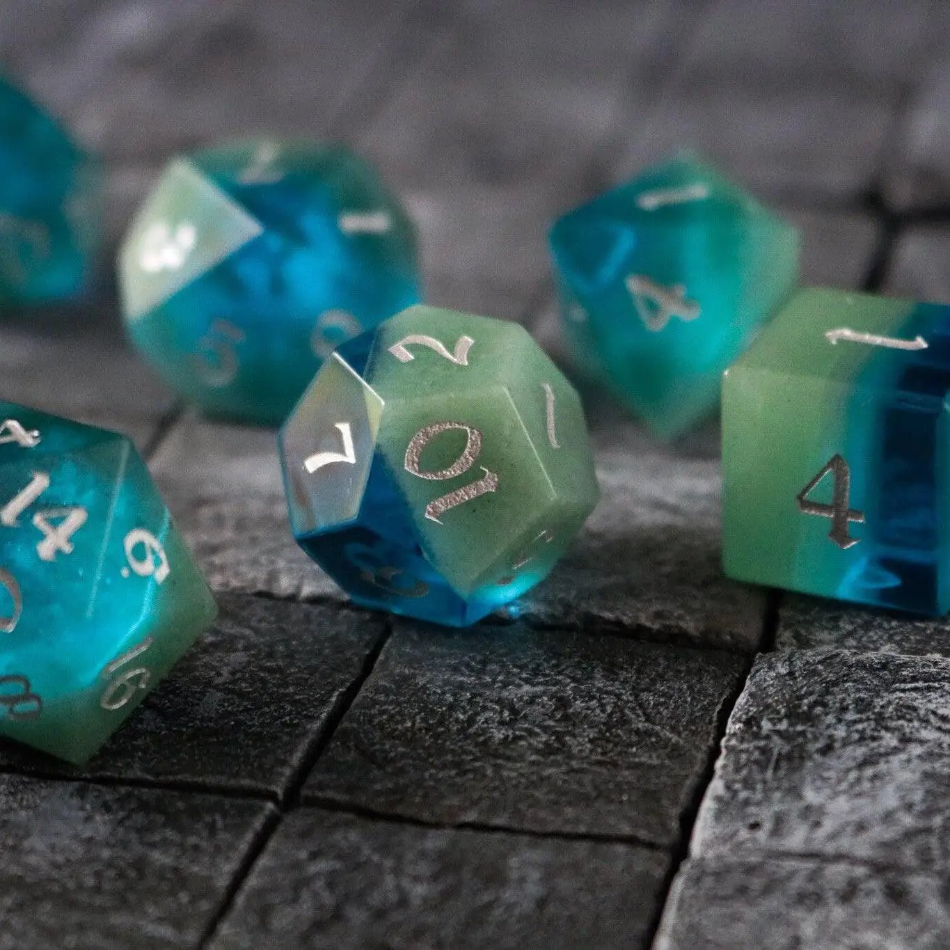 Hand-carved synthetic gemstone DND dice set in two-tone blue and green by Runic Dice, featuring intricate craftsmanship.
