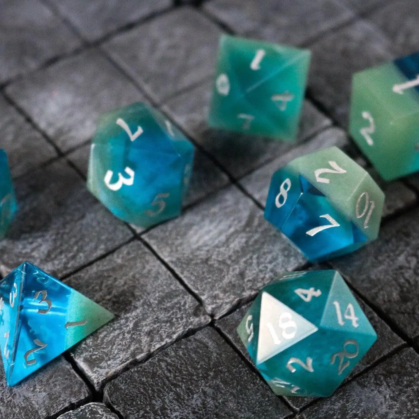 Hand-carved synthetic gemstone DND dice set in two-tone blue and green by Runic Dice, featuring six intricately crafted gemstone dice.