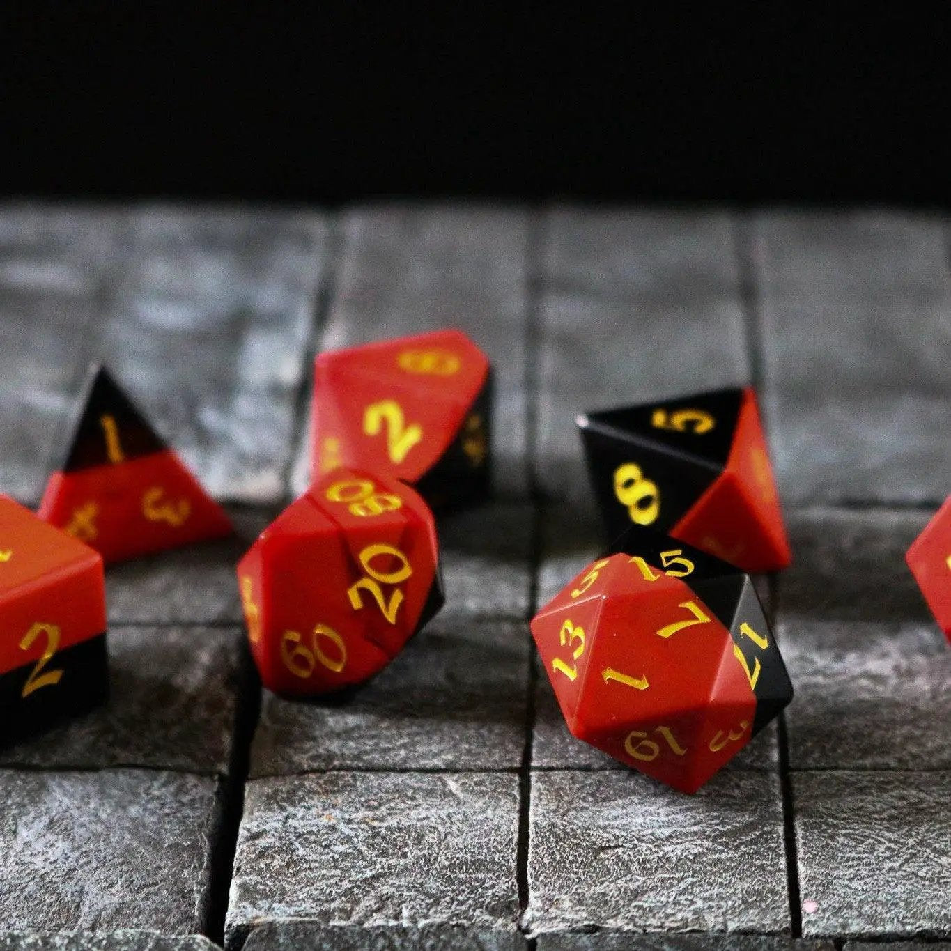 Hand-carved synthetic gemstone dice set in red and black two-tone, designed for D&D gameplay by Runic Dice.