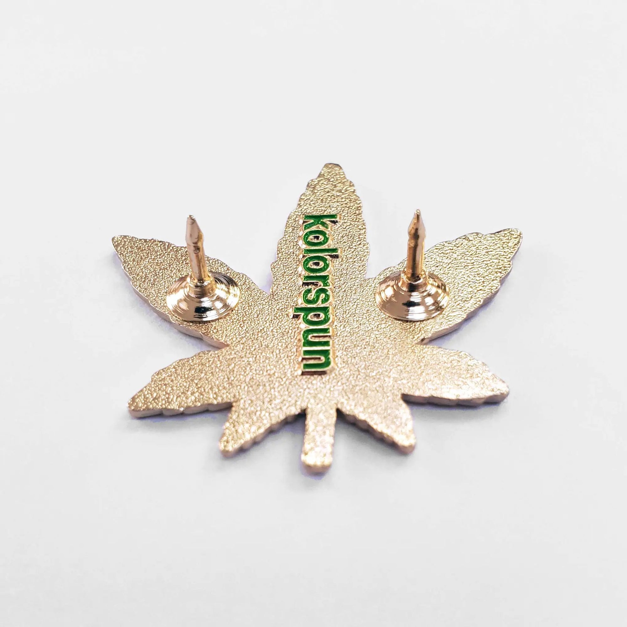 Gold weed leaf pin by Kolorspun featuring detailed metal craftsmanship, perfect for accessory collection or casual wear