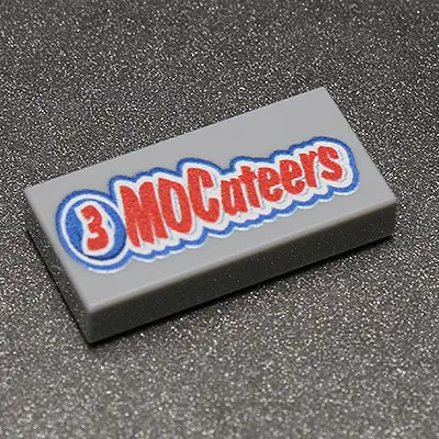 Three custom-printed LEGO 1x2 tiles featuring the 3 MOCateers design by B3 Customs on a white background.
