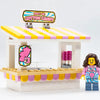 Lego cotton candy stand with Sweet Air branding and a minifigure employee, detailed colorful display for children's play.