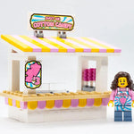 Lego cotton candy stand with Sweet Air branding and a minifigure employee, detailed colorful display for children's play.