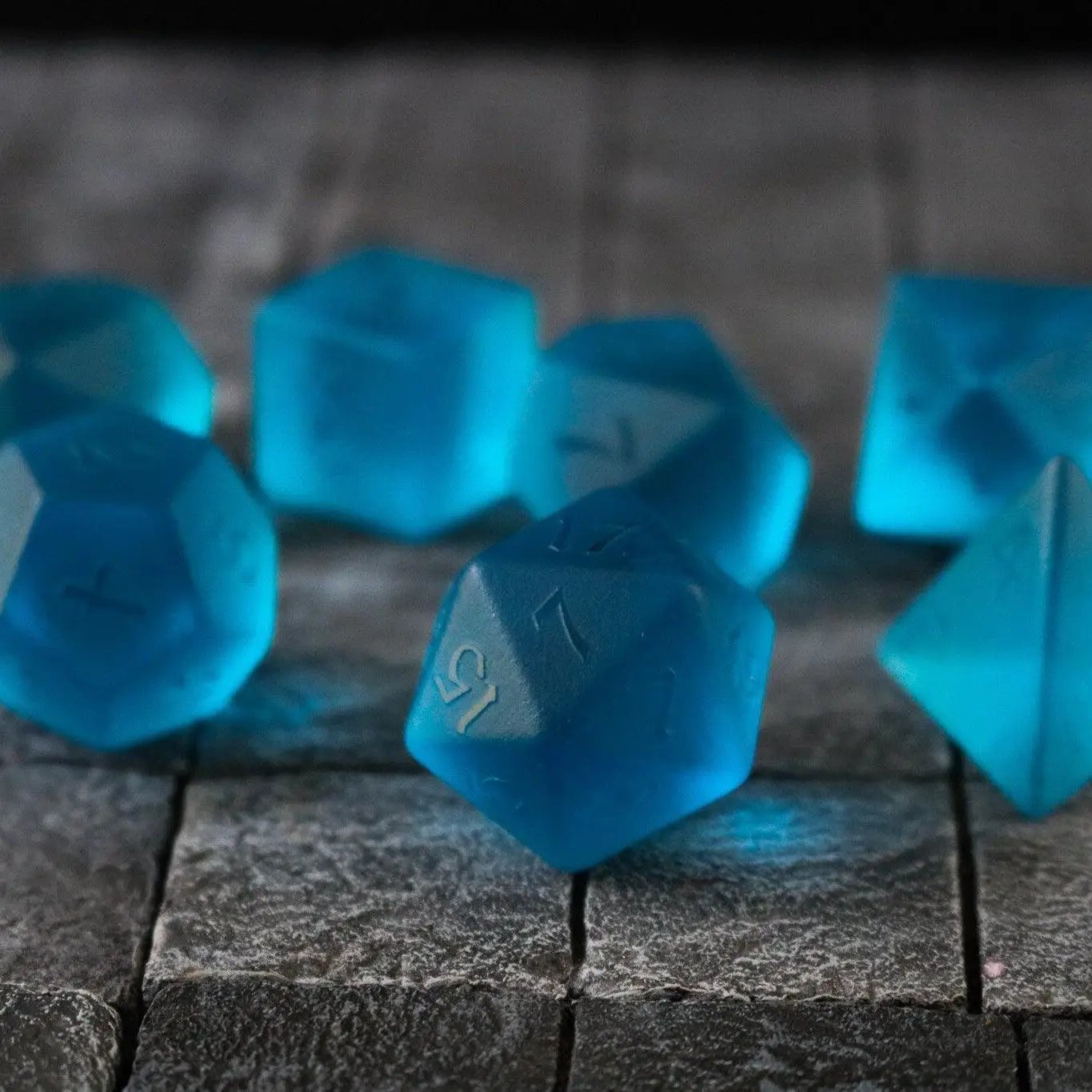 Blue zircon gemstone dice set by Runic Dice, hand-carved glass D&D dice with intricate blue zircon detailing.