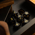 Hand-carved black obsidian gemstone DND dice set by Runic Dice, featuring intricate carvings and polished surfaces for tabletop gaming.