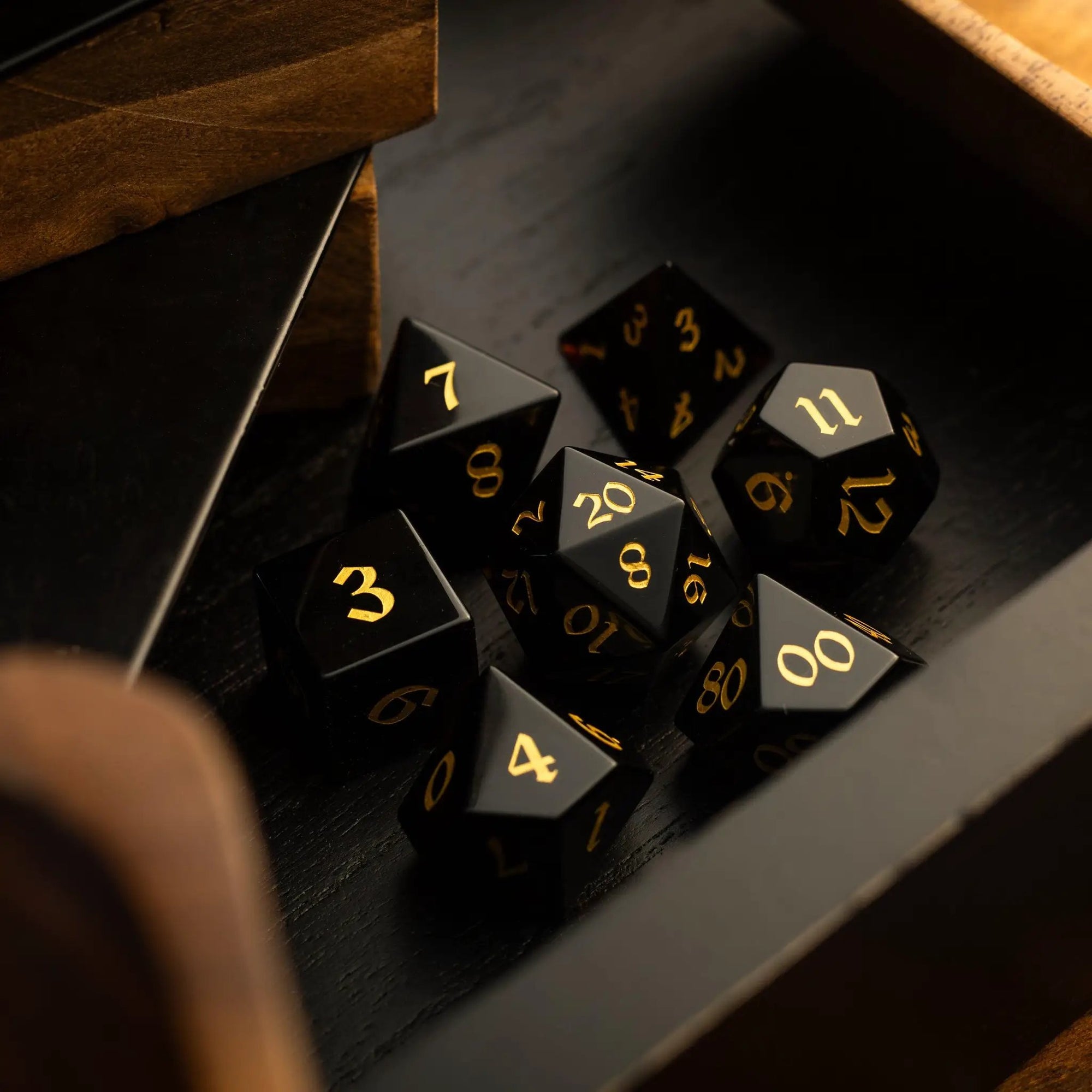 Hand-carved black obsidian gemstone DND dice set by Runic Dice, featuring intricate carvings and polished surfaces for tabletop gaming.