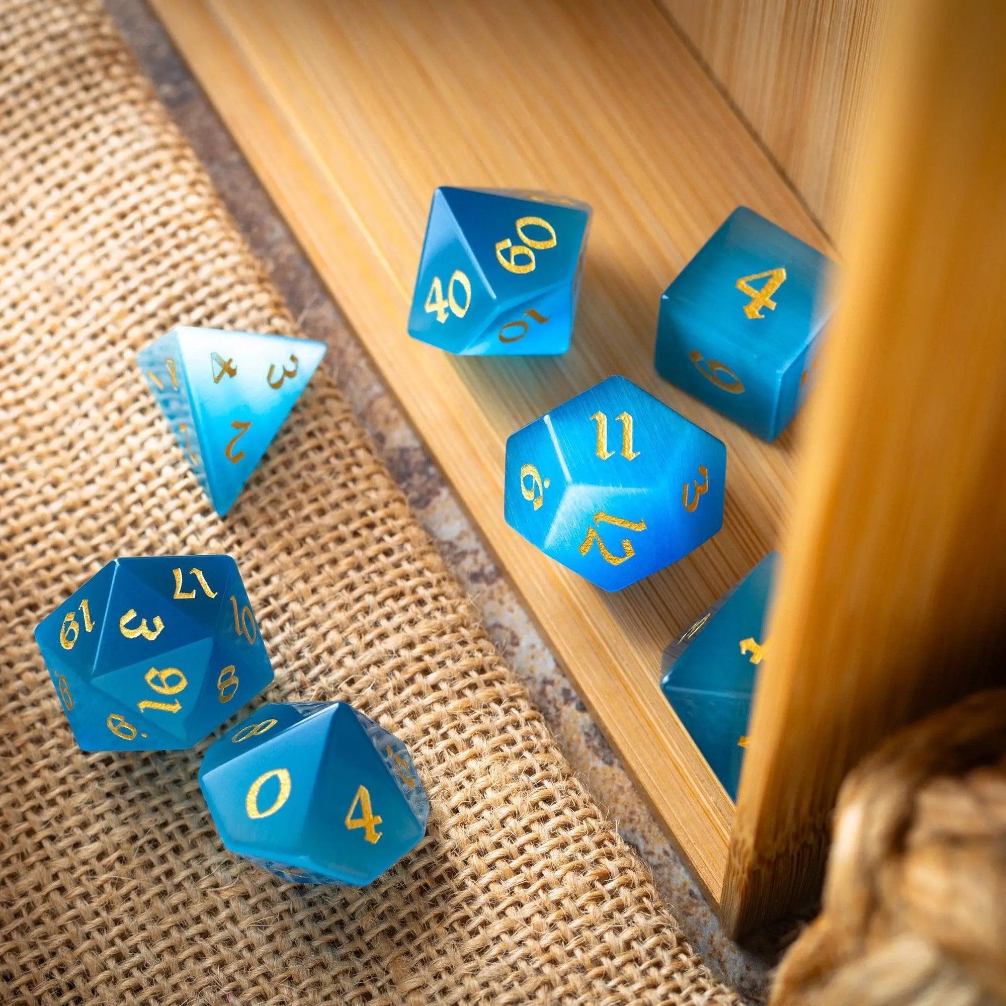 Light blue Cats Eye gemstone D&D dice set hand carved by Runic Dice, featuring intricate gemstone craftsmanship and detailed numbering.