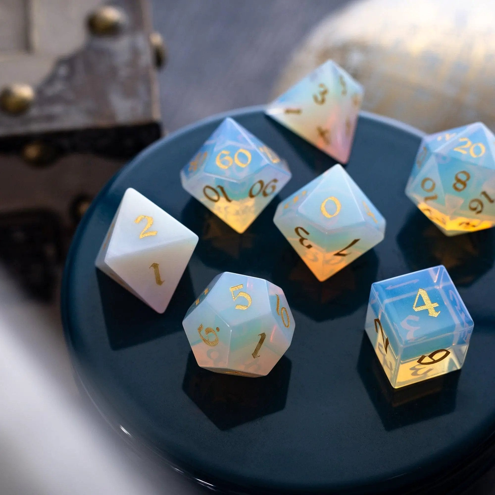 Hand-carved gemstone Opalite DND dice set with gold font by Runic Dice, featuring a variety of colorful, polished gaming dice.