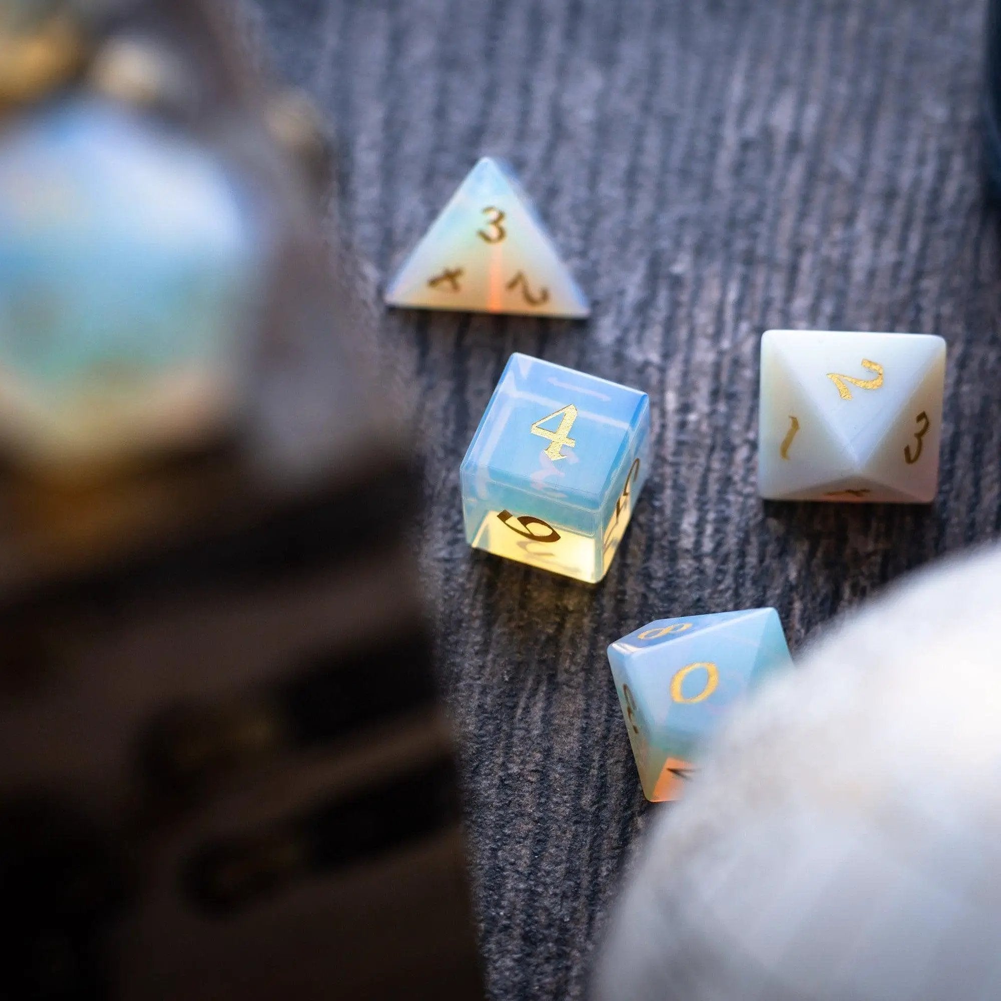 Hand-carved gemstone Opalite DND dice set with gold font by Runic Dice, featuring intricate details and vibrant colors.